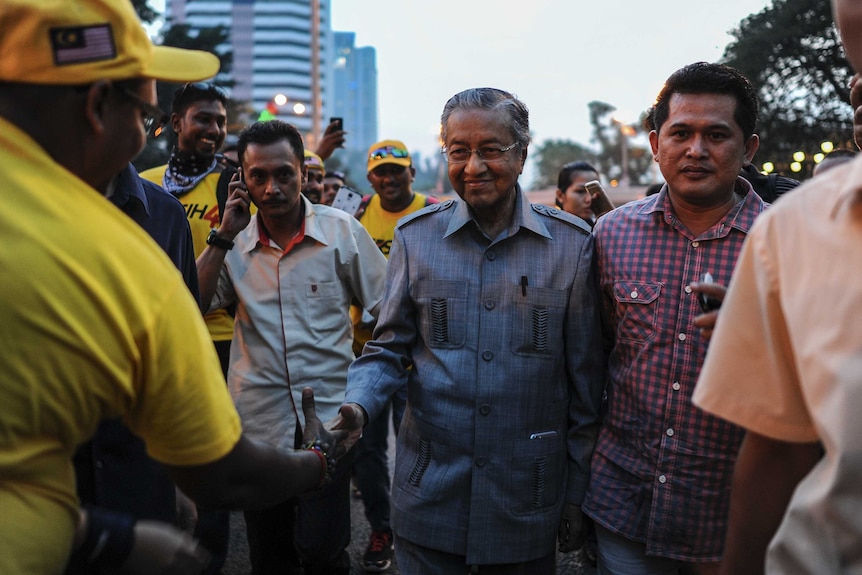 Former prime minister Mahathir Mohamad (C) shakes hands with supporters