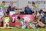 An NRL player dances in celebration after scoring a try.