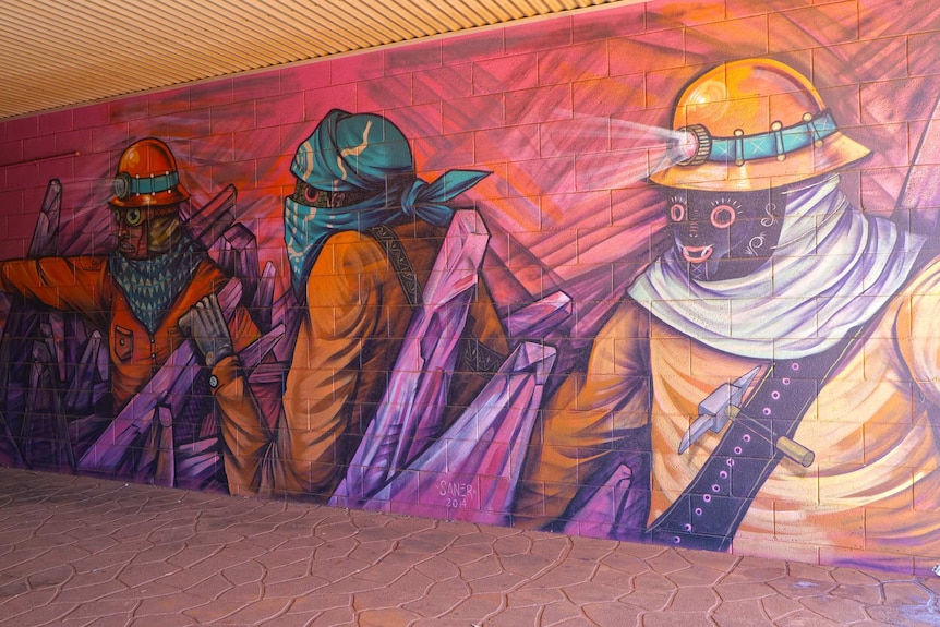 A painting depicting miners in orange suits in a pedestrian underpass.