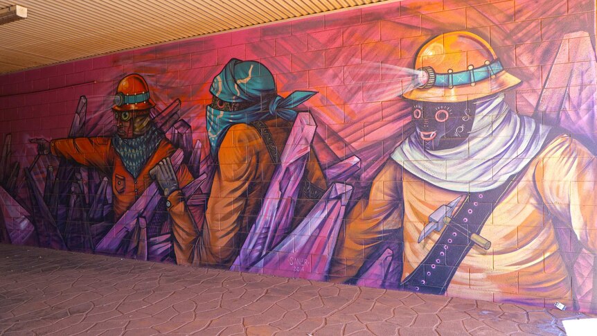 A painting depicting miners in orange suits in a pedestrian underpass.