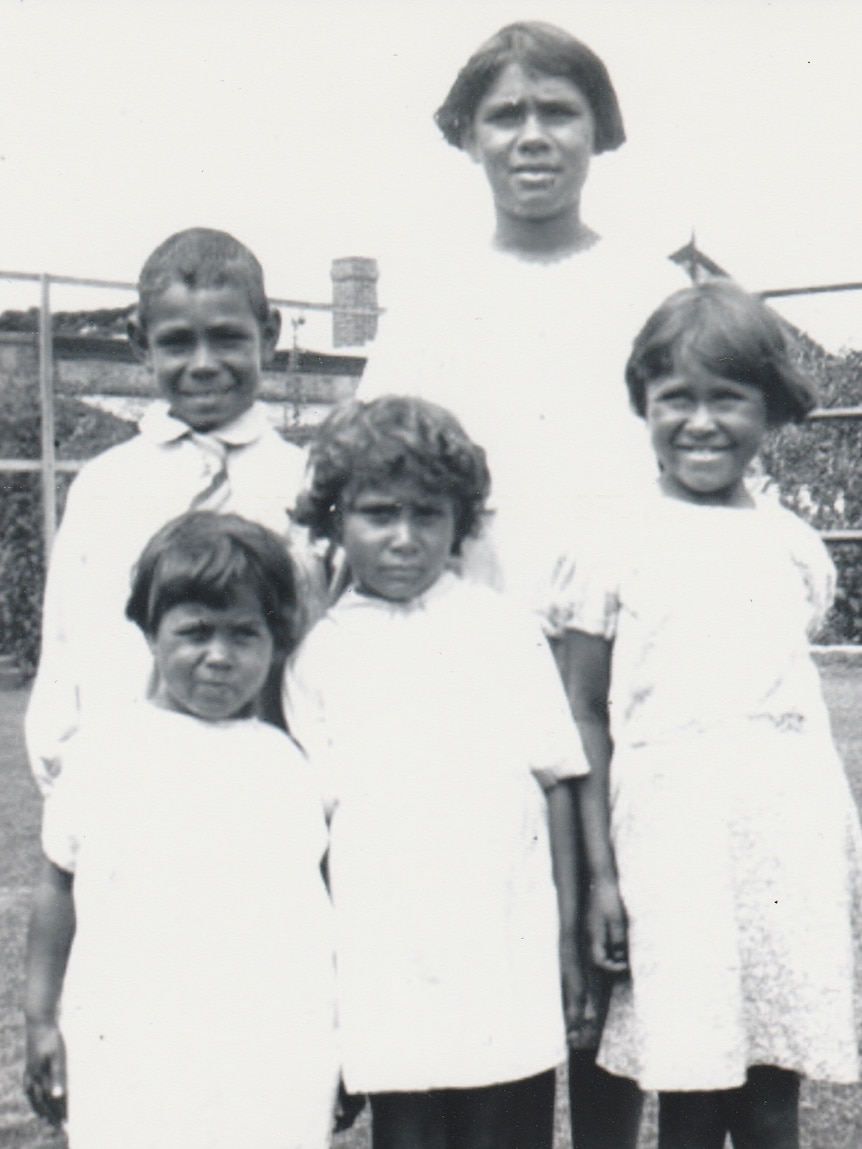 A black and white photo of Indigenous children dressed in white clothing.