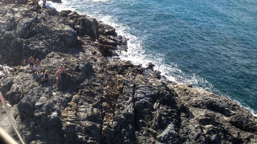 Five people stranded on a rocky outcrop.