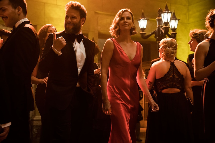 Colour still of Seth Rogen wearing a tux and Charlize Theron wearing a red dress at gala-like event in 2019 film Long Shot.