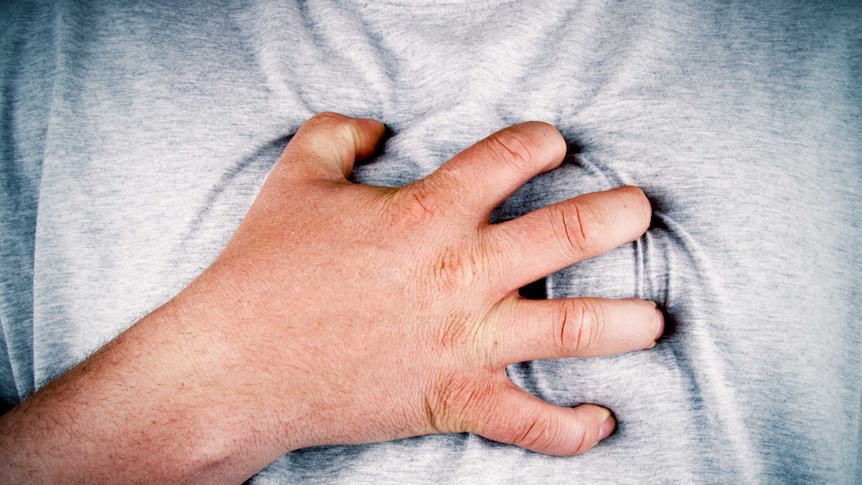 A close up of a man holding his chest.