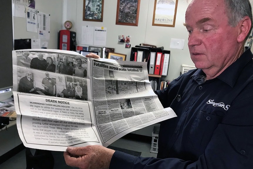 Gordon Simpson holding a "death notice" he put in the paper recently when a sawmill closed in the Rubicon Valley.