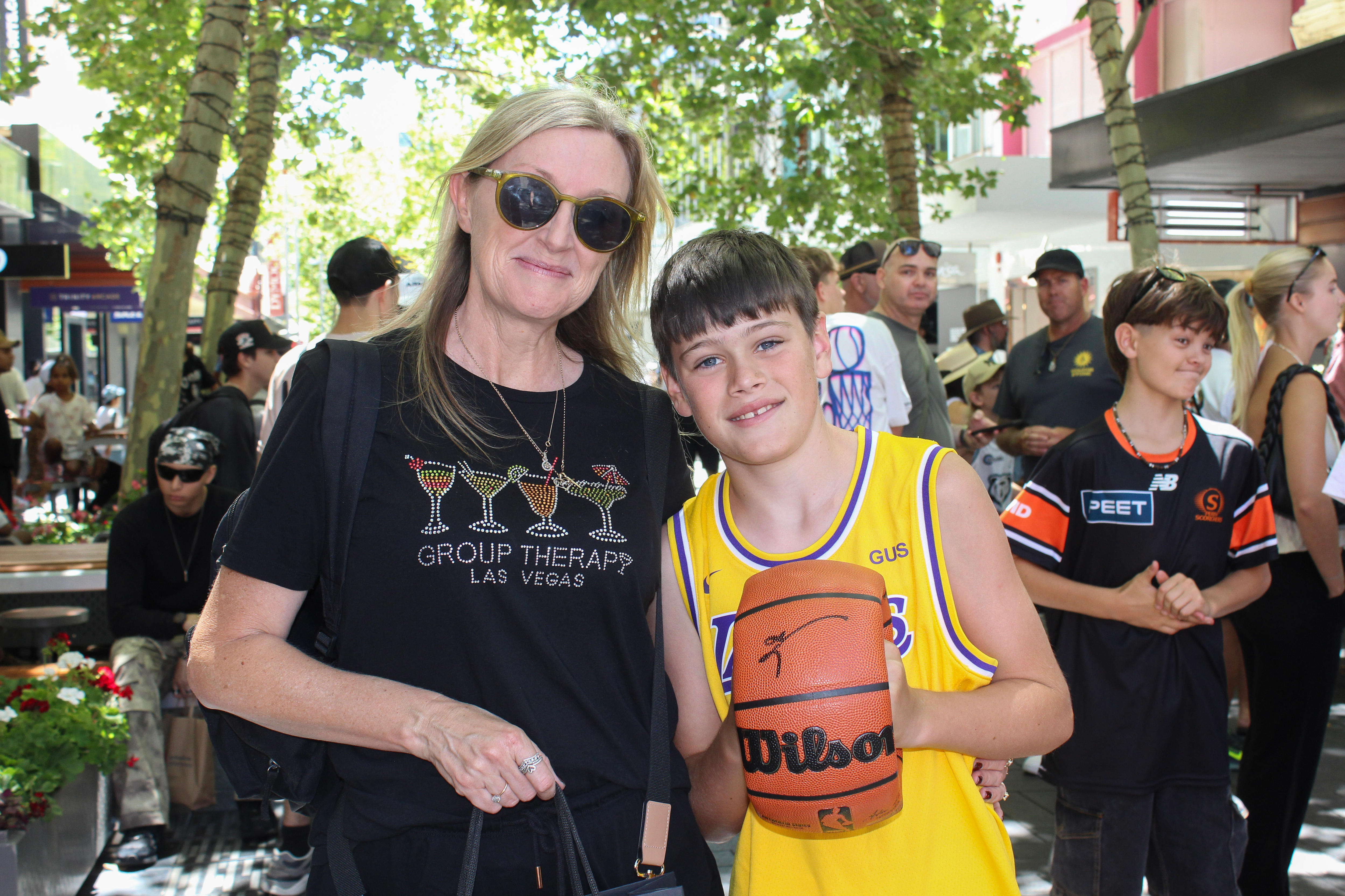 Um menino segura uma bola de basquete autografada ao lado de sua mãe.