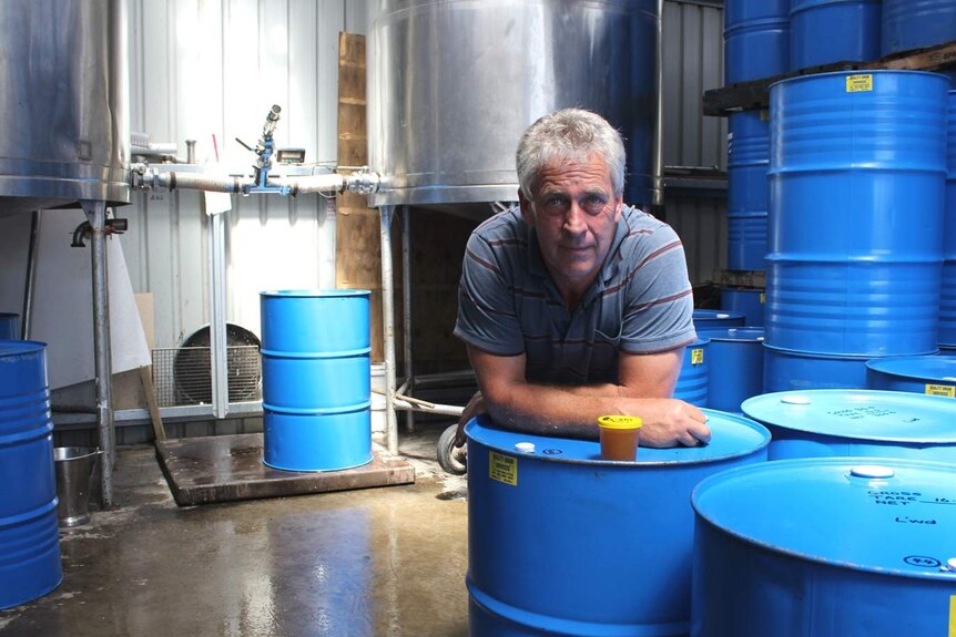Tasmanian apiarist, John Birchenough, leans on a barrel of honey in his processing shed.