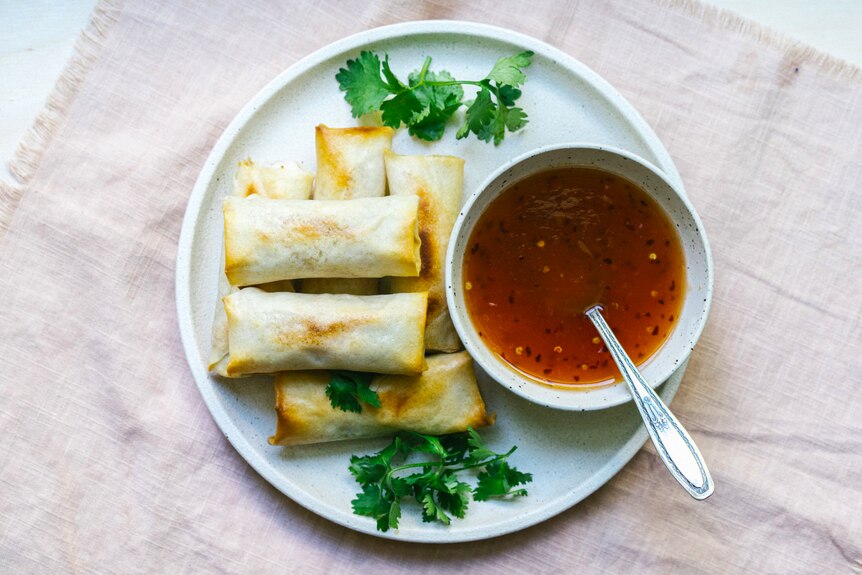 A plate of baked vegetarian spring rolls with homemade sweet chilli sauce by Hetty McKinnon.