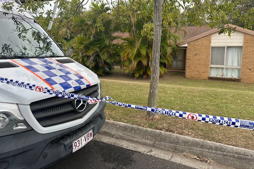 A brick home surrounded by police tape. A police van parked out front. 