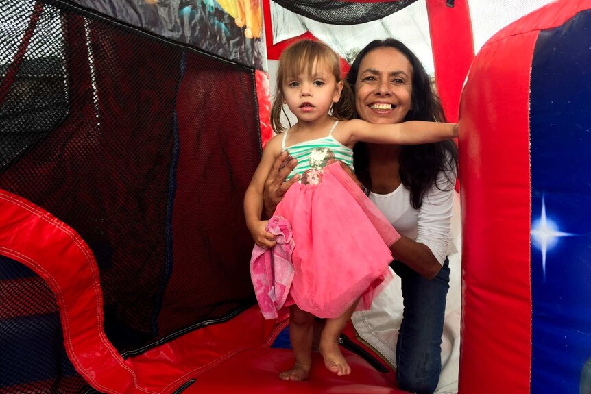 Tanya Day, smiling, holds a small girl inside an inflatable children's play centre.