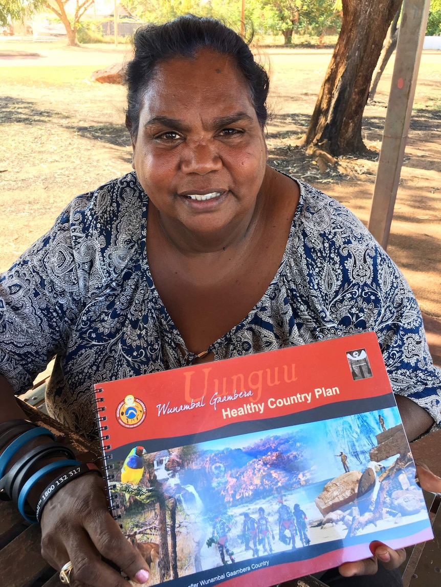 A mid-shot of a smiling Wunambal Gaambera Aboriginal Corporation chair Catherine Goonack holding a book looking at the camera.