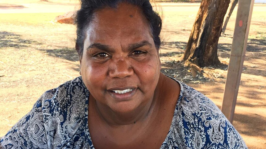 A mid-shot of a smiling Wunambal Gaambera Aboriginal Corporation chair Catherine Goonack holding a book looking at the camera.