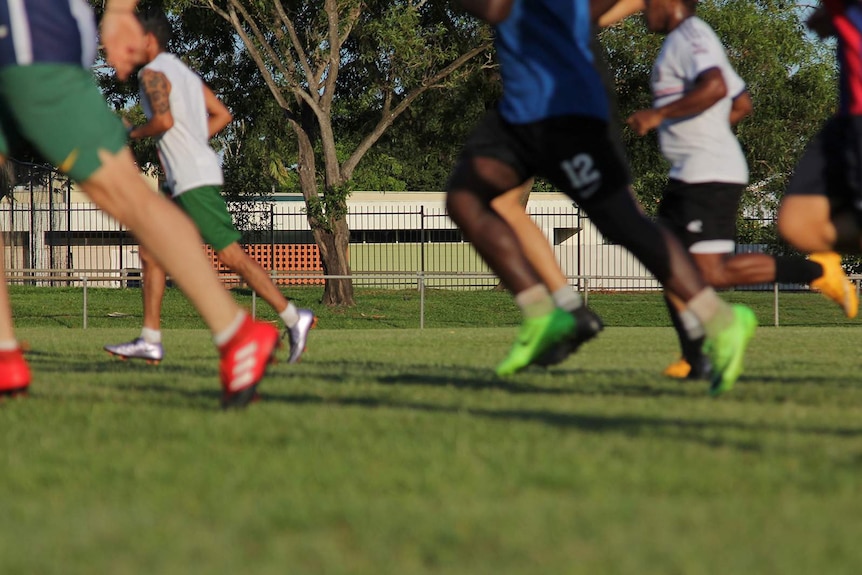 A ground-level shot of several pairs of legs running on a soccer field.