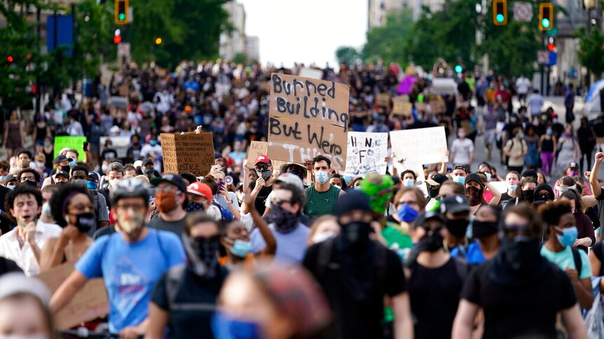 A street filled with demonstrators wearing facemasks.