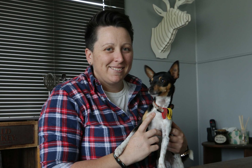 Jane Zerbst sits at her dining table with her dog Roger.