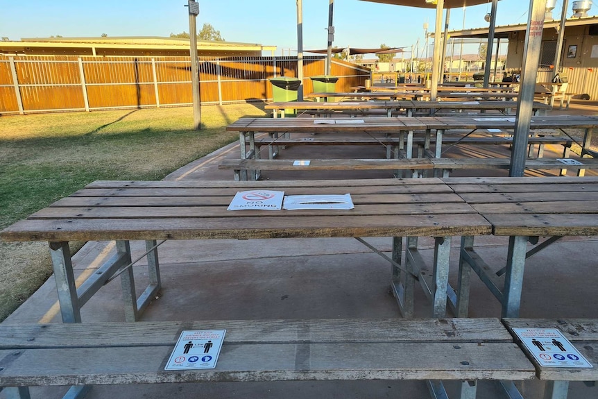 Wooden tables are empty and signs are stuck on the top reminding of social distancing 1.5 metres