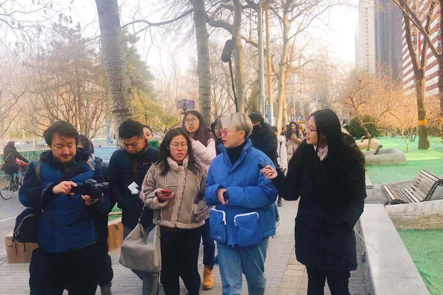 身穿蓝色外衣的Teresa Xu与媒体在一起。