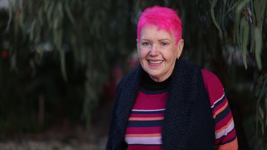 Older woman with pink hair in a pink jumper.