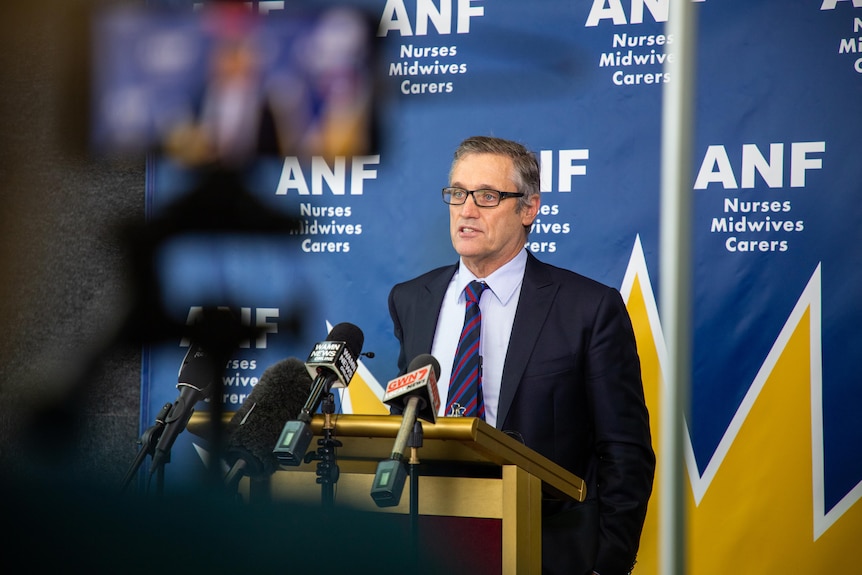 Australian Nursing Federation state secretary Mark Olsen speaking at a media conference in front of a camera.