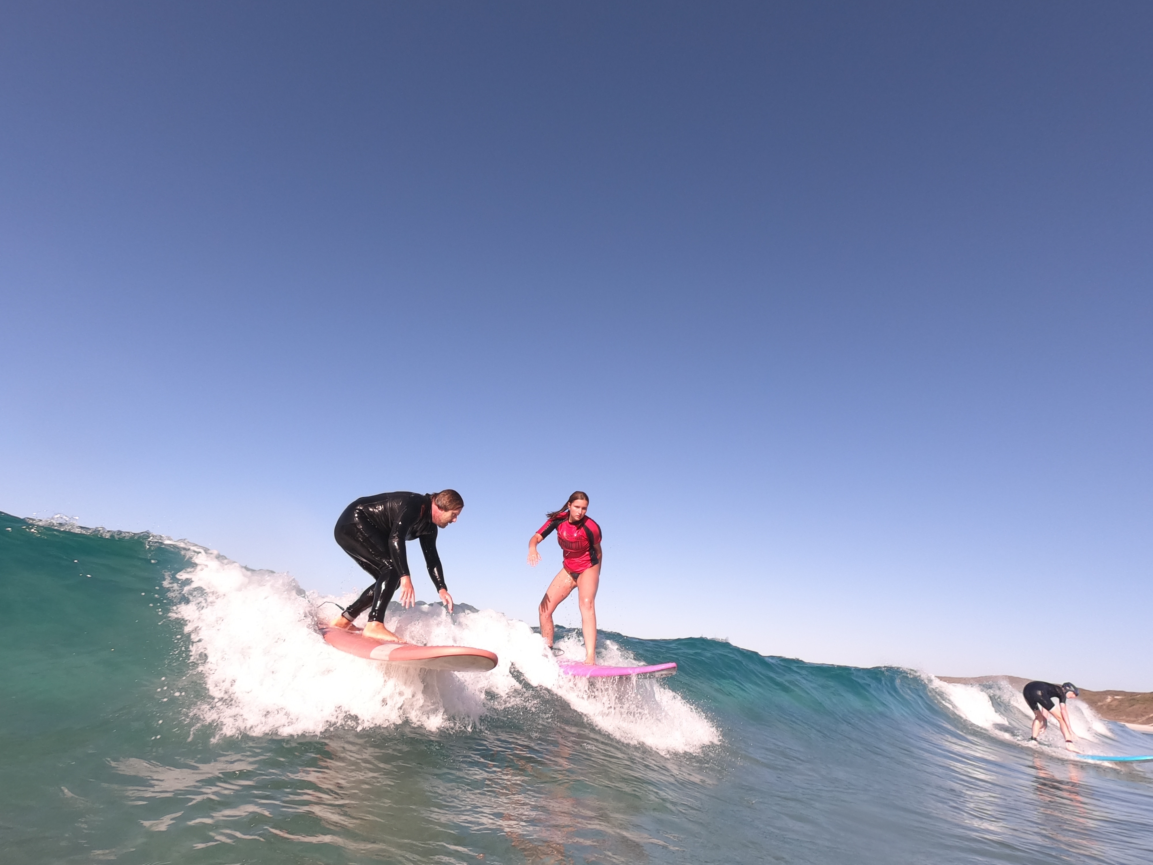 Tres personas surfean una ola. 