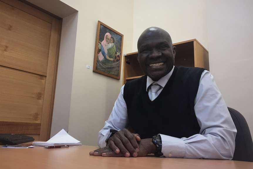 A man sitting at a table and smiles at the camera