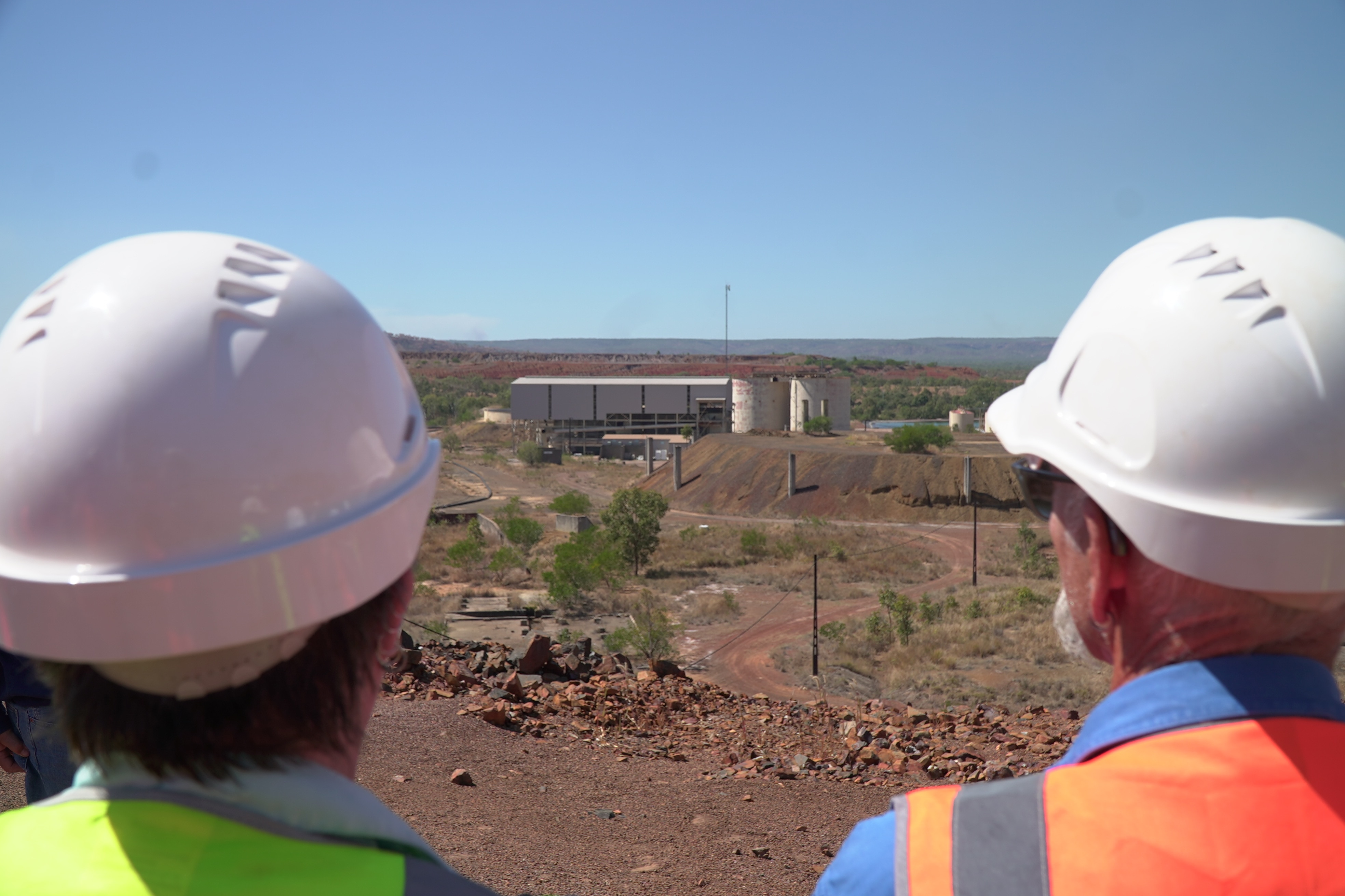 Two miners look at a building in the distance.