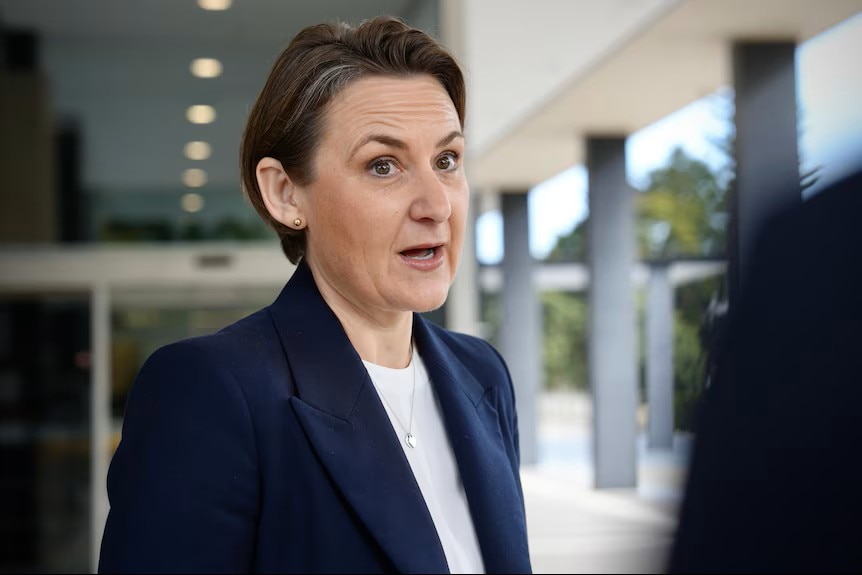 AMBER-JADE SANDERSON EM UM BLAZER MARINHA E UMA CAMISA BRANCA FALA