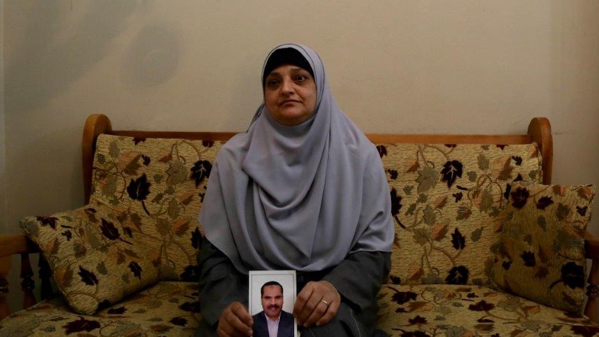 A woman sits on a sofa clutching a photo