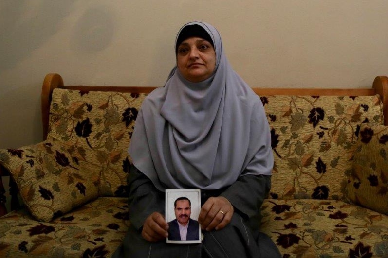 A woman sits on a sofa clutching a photo