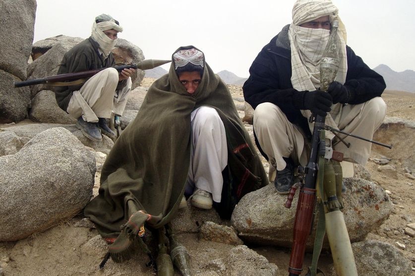 Several men in traditional Afghan clothing with their faces covered and holding rocket launchers.