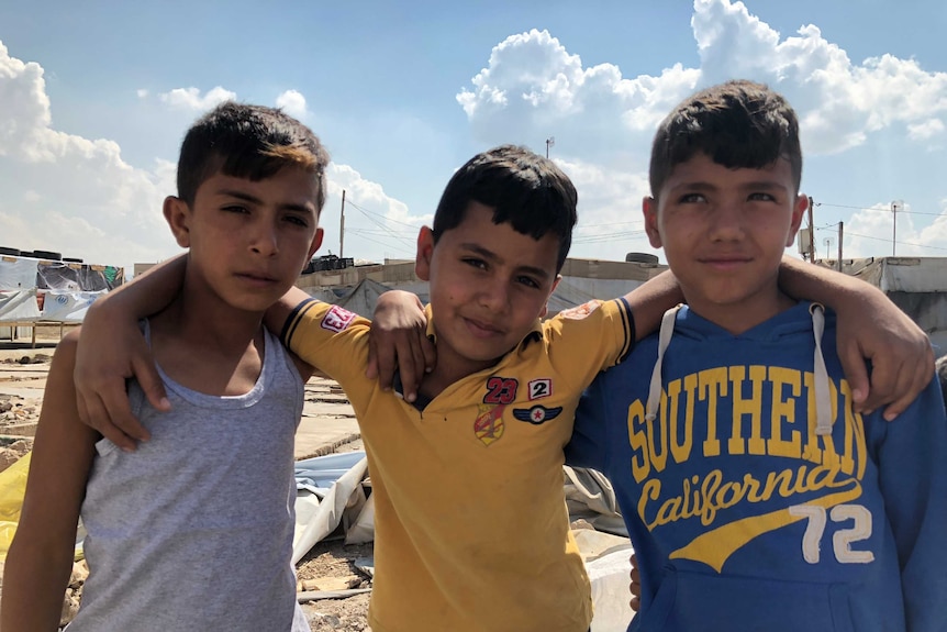 Three boys living in a refugee camp link arms