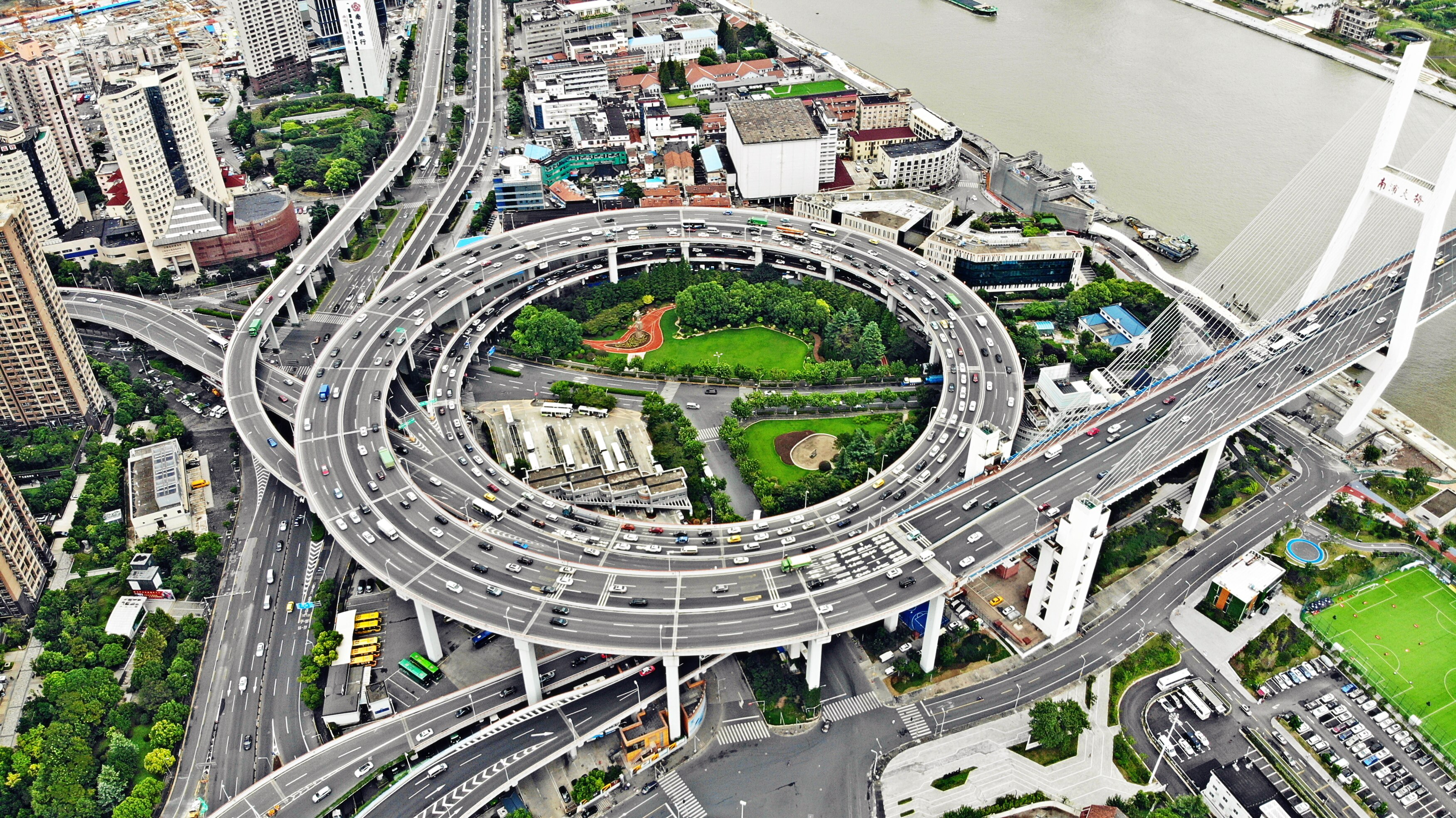 A complicated highway network with several roads feeling into large circular road, green gardens in the middle