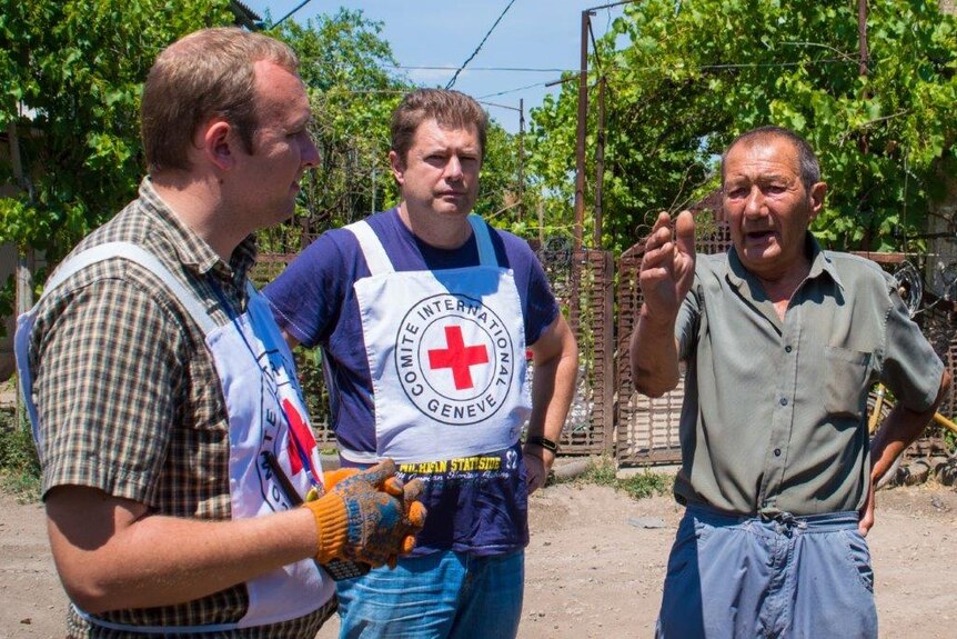Alex Vlasenk, wearing an identifying red cross bib, speaks to a villager in eastern Ukraine.