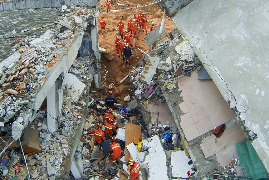 Rescue workers search among the debris of destroyed buildings after a landslide hit an industrial park in Shenzhen, China