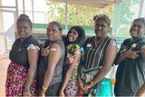 Five women stand showing off their COVID-19 vaccination. 