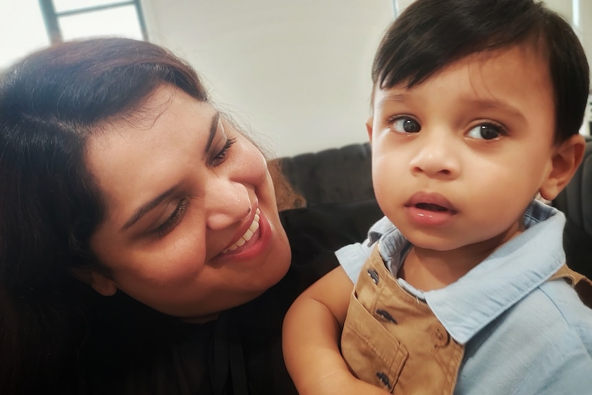 Feroza holds looking at her young son, who looks at the camera