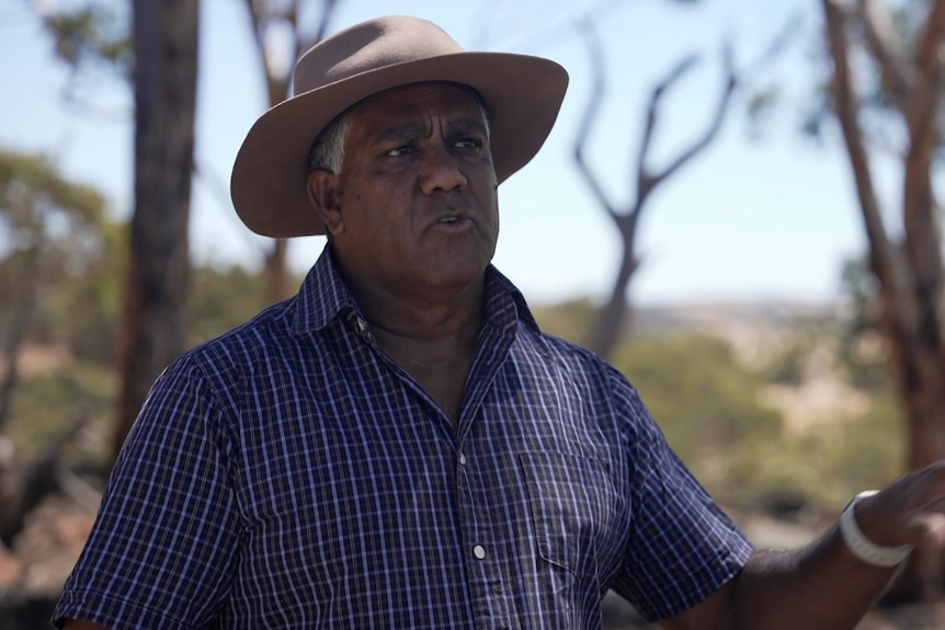 Photo of an man talking to the camera with native bush behind him.