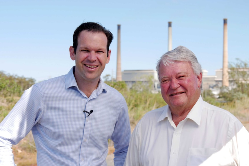 Two men stand in front of a coal fired power station in central Queensland