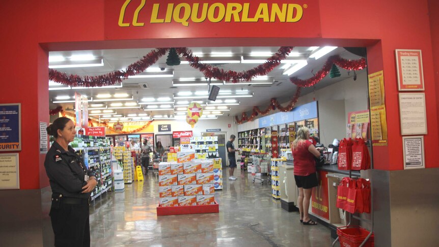 A security guard stands outside a Liquorland store.