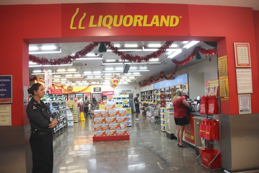 A security guard stands outside a Liquorland store.