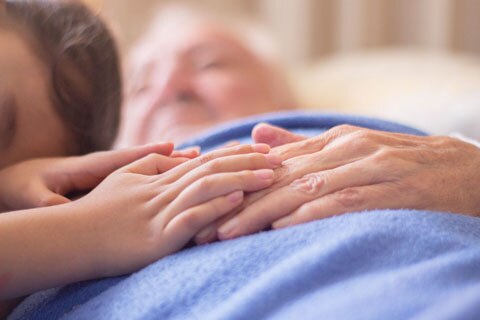 Young girl's hands resting on old woman's hands