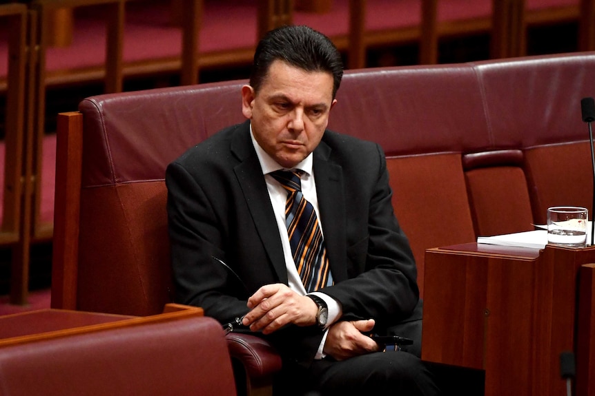 Senator Nick Xenophon sits alone with a pensive look on his face.