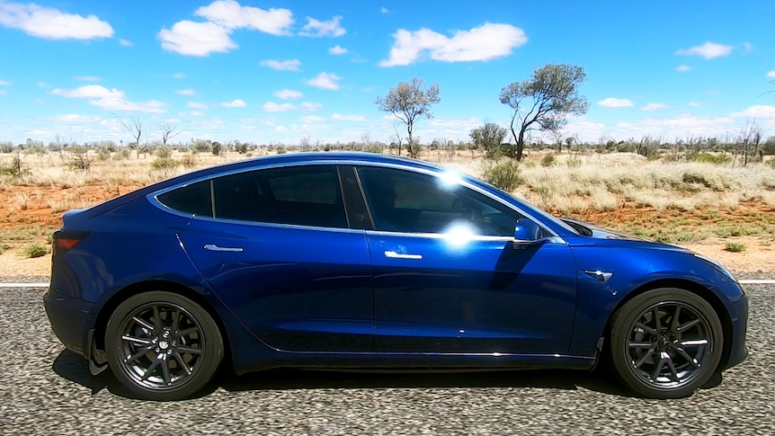 A Tesla drives on a desert highway