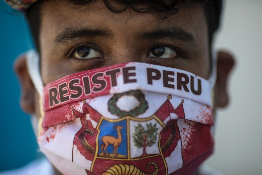 A close up of a person with brown eyes with a face mask reading the Spanish message "Resist Peru".