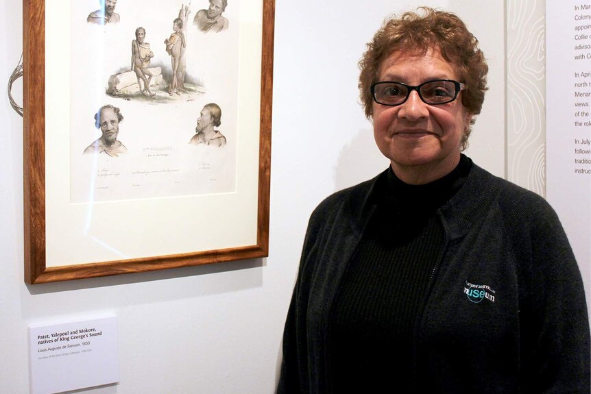 Vernice Gillies Menang elder next to some sketches of Aboriginal people from the 1800s.