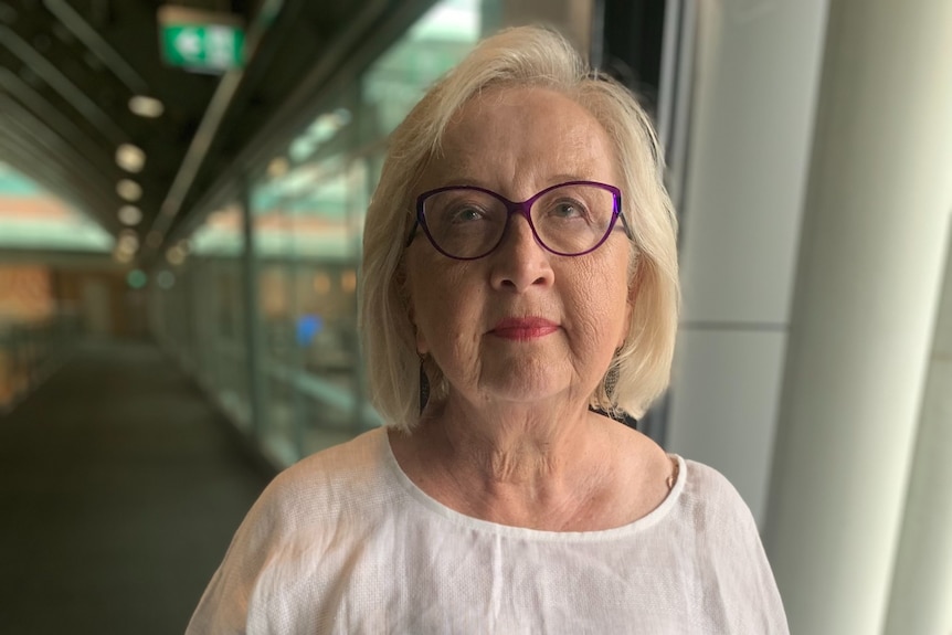 A woman wearing glasses poses for a portrait with a serious expression.