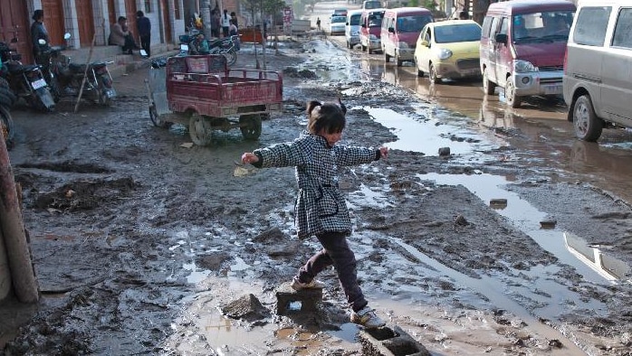 Girl skips over storm-muddied street