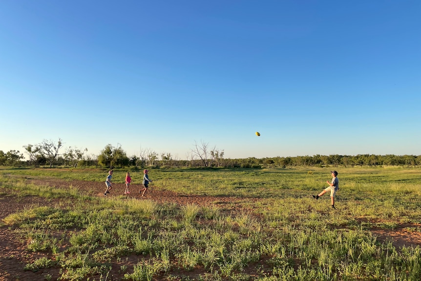A group of young boys kicking a football on an outback station