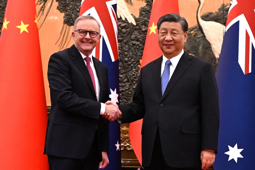 Anthony Albanese shakes hands with Xi Jinping in front of the Australian and Chiense flags in Beijing.