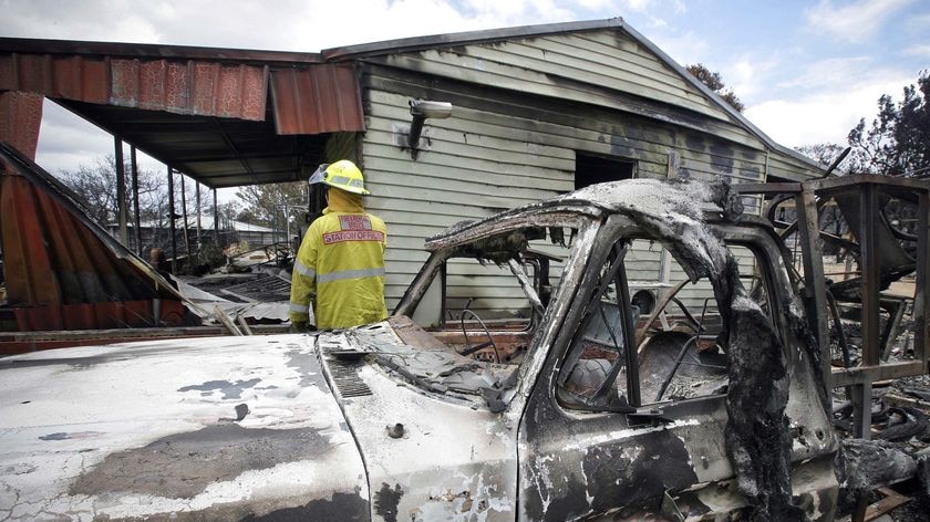 A firefighter inspect the damage caused by bushfires at the small country town of Toodyay
